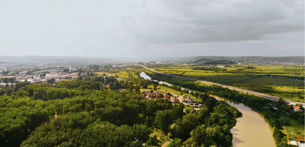 Arial view of Pitești, Romania featuring a meandering river, houses and road infrastructure.