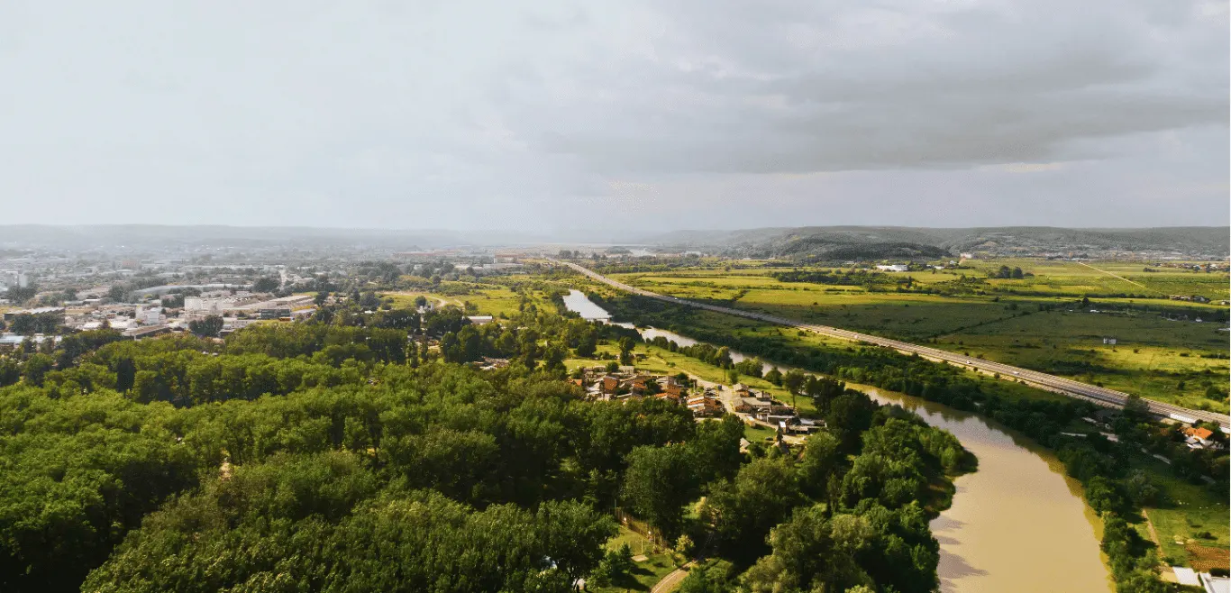 Arial view of Pitești, Romania featuring a meandering river, houses and road infrastructure.