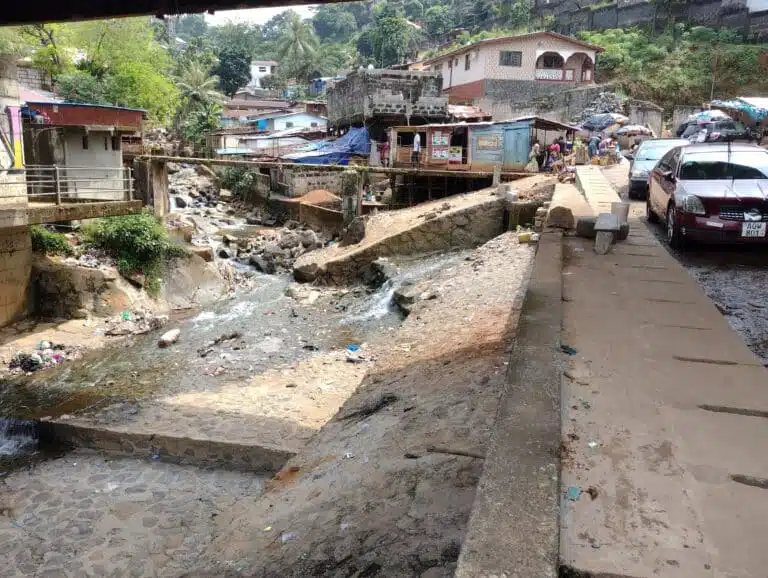 River channel in Freetown, Sierra Leone, flowing through an urban setting under a bridge, highlighting flood risk challenges addressed by JBA Global Resilience.