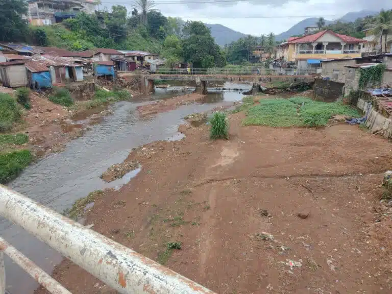 Houses next to a river channel in Freetown, Sierra Leone, highlighting the challenges of flood risk addressed by JBA Global Resilience's hydromet services.