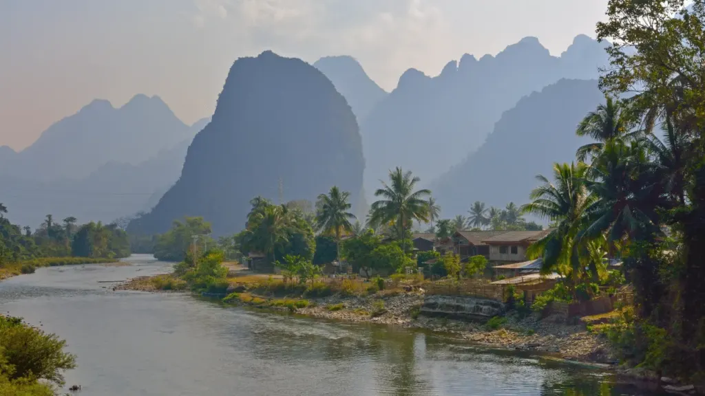 Rural scene of a river and settlement in the forefround and mountain range in the background. Lao PDR.
