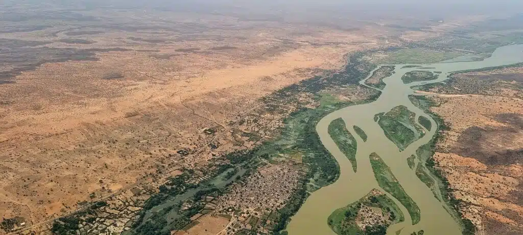 Aerial photograph of uban centre next to a large, meandering river. Surrounded by arid landscape.
