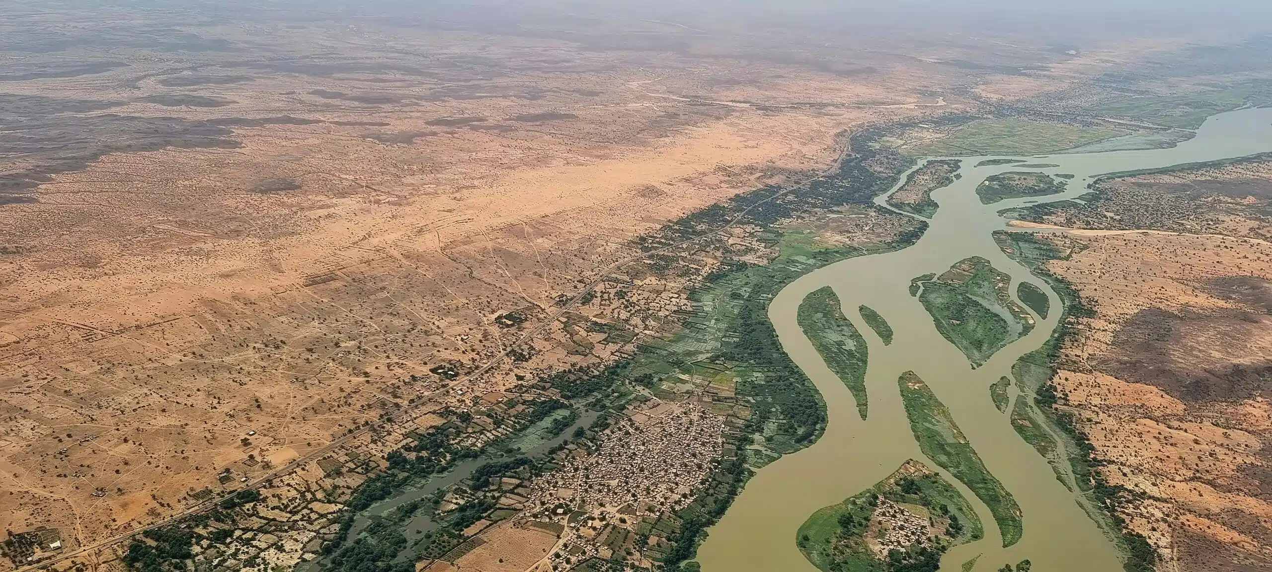 Aerial photograph of uban centre next to a large, meandering river. Surrounded by arid landscape.