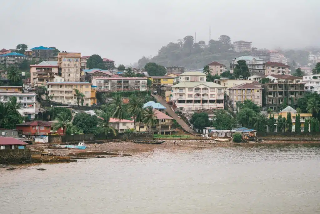 Hillside view of Freetown, Sierra Leone, with waterfront buildings during heavy rainfall, highlighting urban flood risk in West Africa.