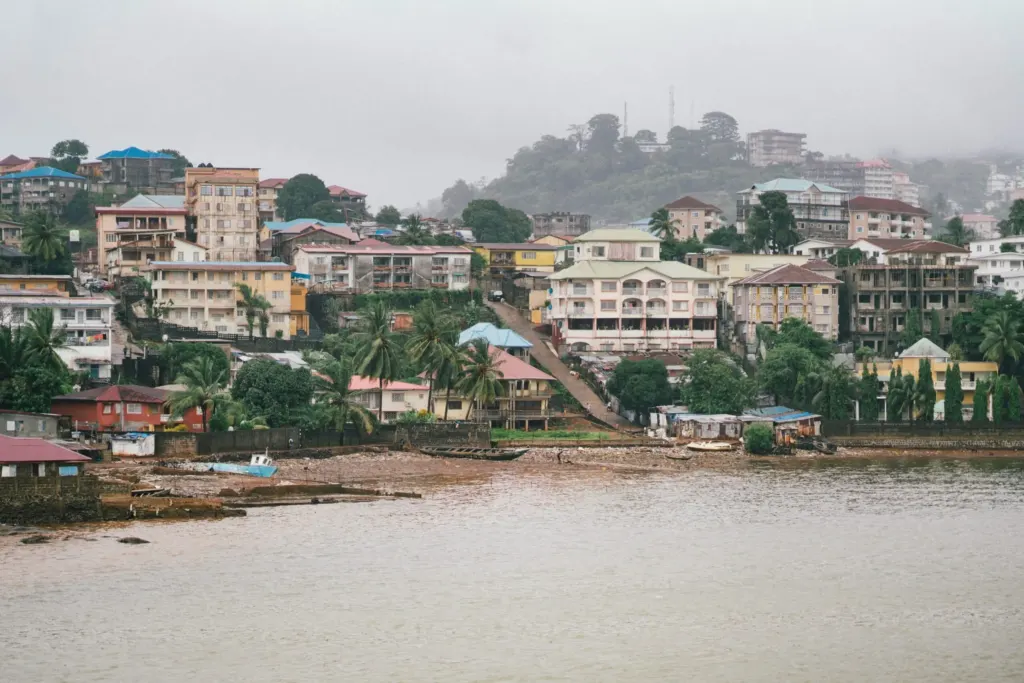 Hillside view of Freetown, Sierra Leone, with waterfront buildings during heavy rainfall, highlighting urban flood risk in West Africa.