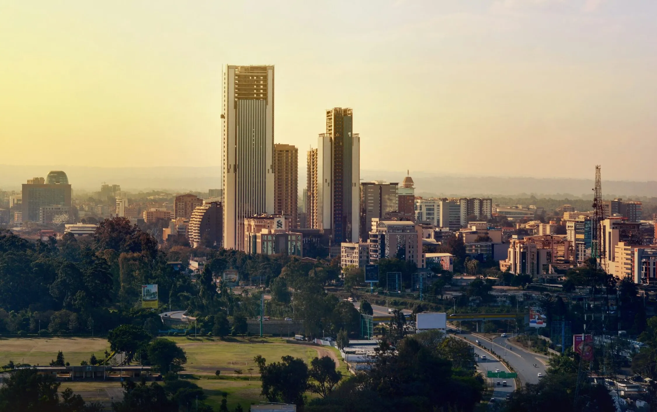 Nairobi city skyline with high‑rise buildings, green open space in the foreground, and surrounding urban development.