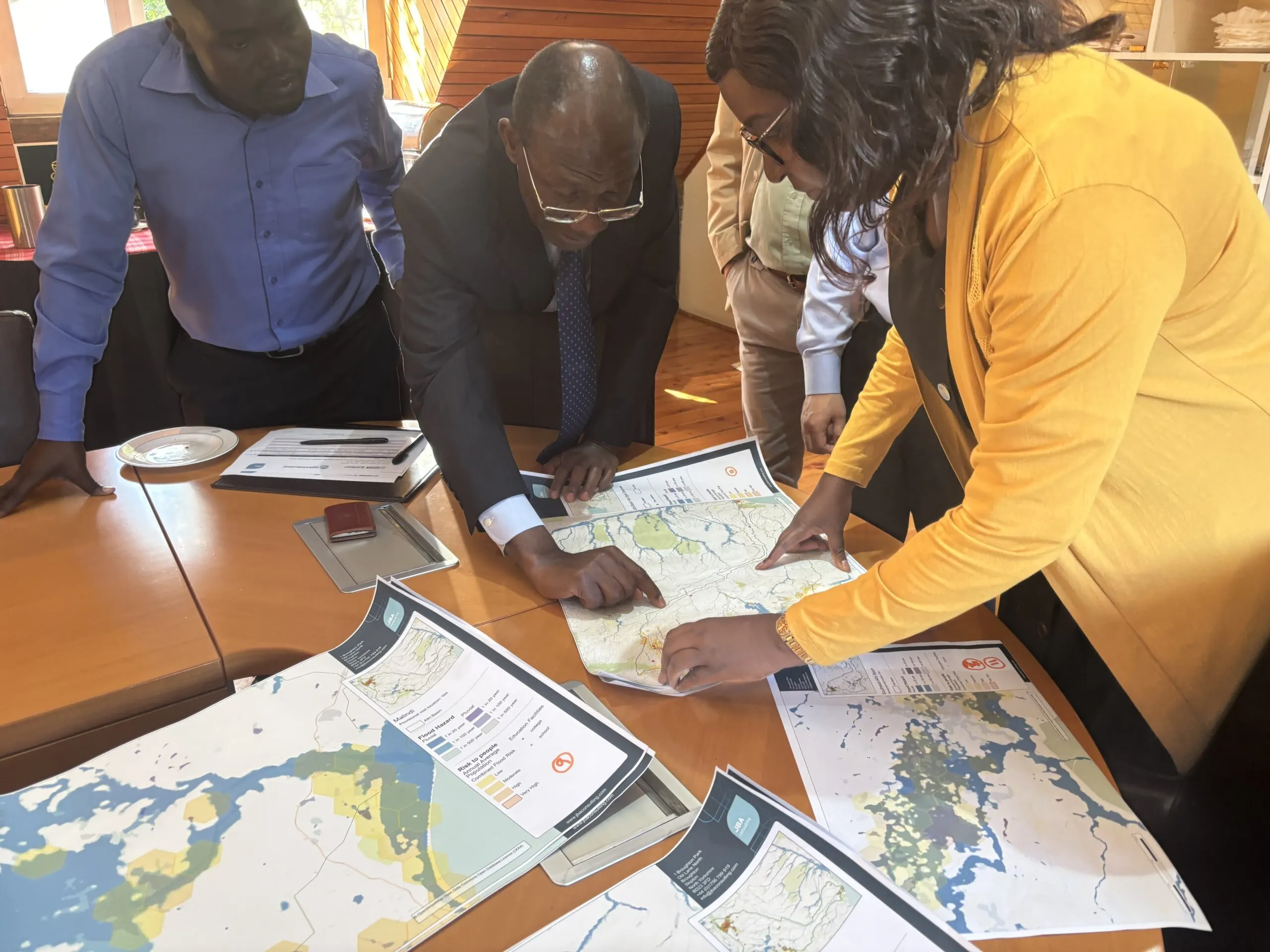 Group of stakeholders reviewing printed flood risk maps during a project discussion session.