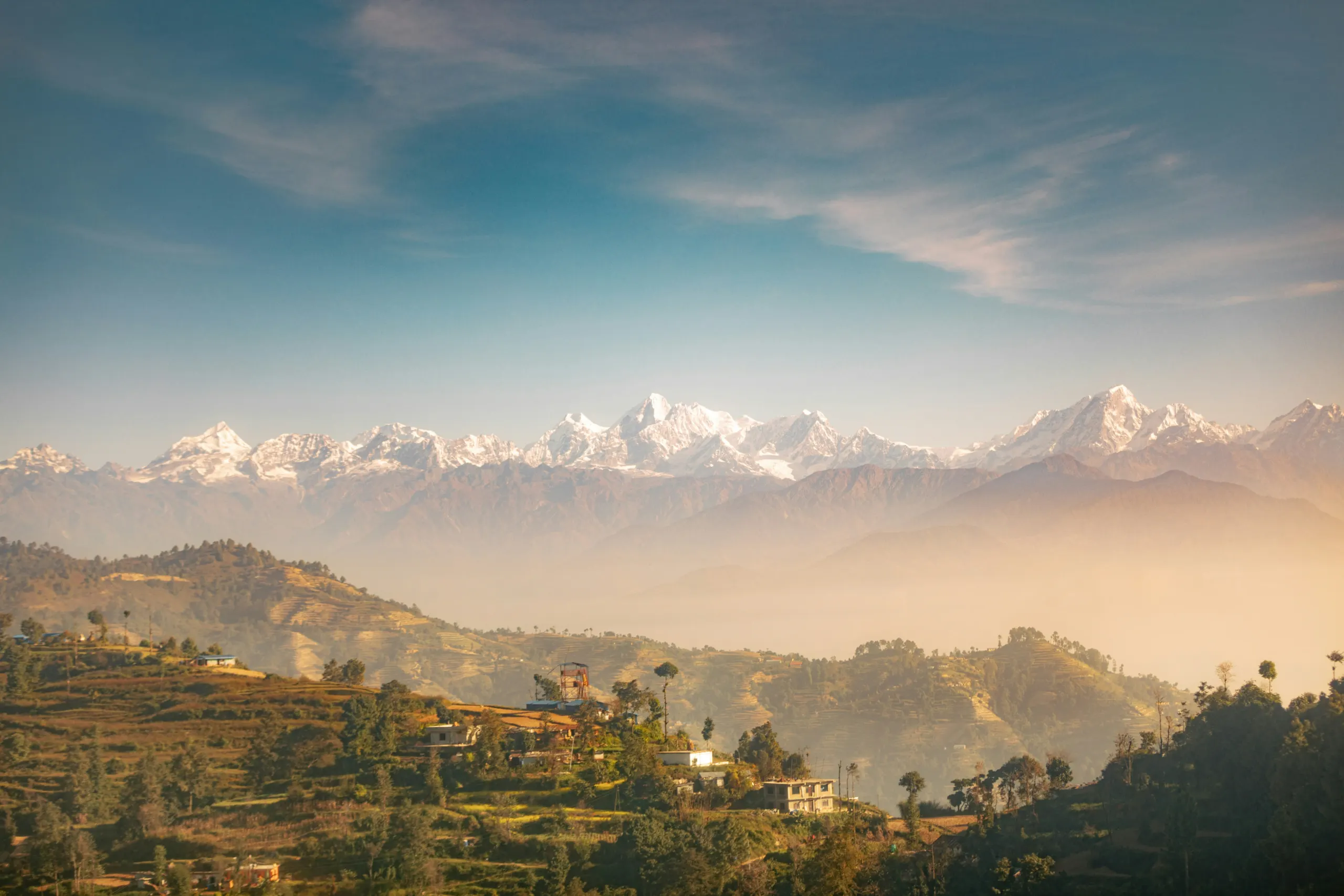 View of the Himalayan mountain range above terraced landscapes and rural settlements in Nepal.